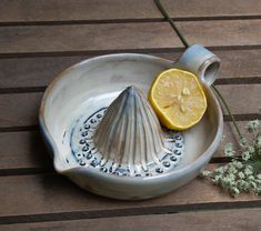 a ceramic dish with a lemon slice on it next to a flower and a tea strainer