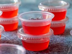 plastic cups filled with red liquid sitting on top of a table