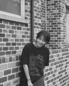 a young man leaning against a brick wall