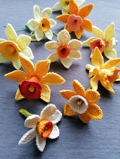 crocheted flowers are arranged on a blue tablecloth with white and yellow petals