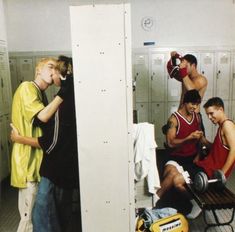 several men in lockers with one drinking from a bottle