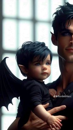 a man holding a small child in his arms with wings on it's chest