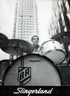 a man playing drums in front of a tall building with the words singerland on it