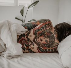 a woman laying in bed with tattoos on her stomach