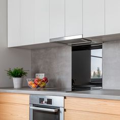 a bowl of fruit sitting on top of a counter next to a stove and oven