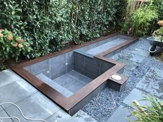 an outdoor hot tub surrounded by greenery and graveled area with plants on either side