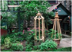 two wooden lanterns sitting next to each other in front of a brick building and garden