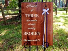 a wooden sign with a key hanging from it's side in front of some grass