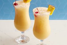 two cocktails with pineapple garnish on the top and one has a cherry in it