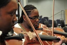 two women are playing violin in an orchestra