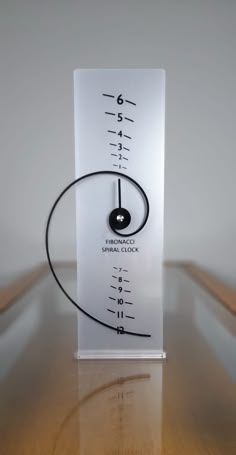 a clock on top of a wooden table next to a white sign that says fidgetnaci spiral clock