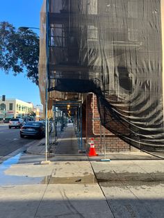 an empty city street with cars parked on the side walk and covered by a tarp