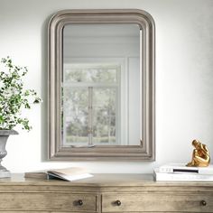 a large mirror sitting on top of a dresser next to a vase filled with flowers