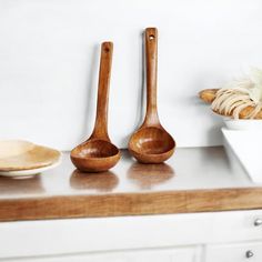 three wooden spoons sitting on top of a counter next to a bowl and plate