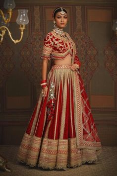 a woman in a red and gold bridal gown standing next to a chandelier