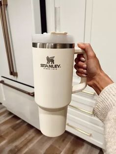 a person holding a coffee cup in front of an oven with the word stanley on it