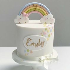 a white cake decorated with rainbows and clouds