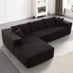 a large black couch sitting on top of a white rug