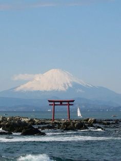 a large red object sitting on top of a body of water next to a mountain