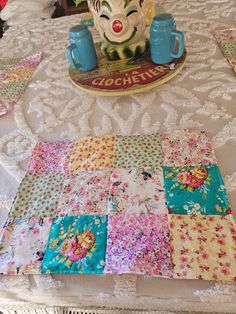 a table topped with lots of colorful cloths and a teapot on top of it