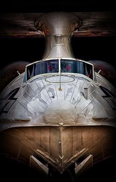 the nose of an airplane that is parked in a hangar with it's lights on