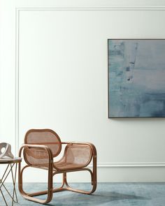 two chairs in front of a table with a painting on the wall behind it and another chair to the side