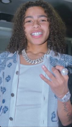 a young man with long curly hair wearing a ring