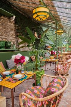 an outdoor dining area with wicker chairs and colorful tablecloths on the tables