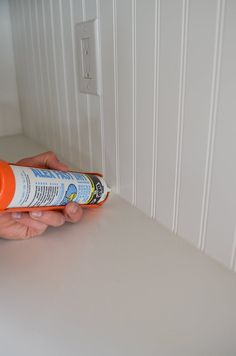 a person is holding an orange tube with toothpaste on it and cleaning them