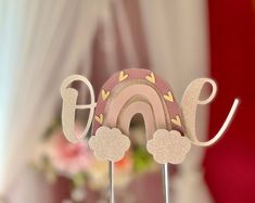 a cake that is shaped like the word love with clouds and a rainbow on top