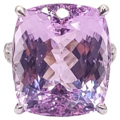 This stunning cocktail ring features an IGI Certified 24.20 Carat Kunzite in an intense purplish pink color and cushion shape, set in 18K white gold. The vibrant Kunzite gemstone is complemented by 30 white round brilliant diamonds totaling 0.47 carats, adding a touch of sparkle and elegance to the piece. The stylish design of the ring makes it perfect for daily wear, effortlessly combining luxury with versatility. The bold color of the Kunzite and the shimmer of the diamonds create a captivating and eye-catching piece that is sure to make a statement wherever it is worn. Color Rosa, Cocktail Ring, Cocktail Rings, Round Brilliant, Bold Colors, Pink Color, Diamond Ring, Jewelry Rings, Gems