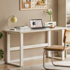 a laptop computer sitting on top of a white desk next to a chair and potted plant