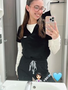 a woman taking a selfie in front of a bathroom mirror with her cell phone