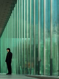 a man standing in front of a tall building with lots of glass on the walls