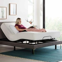 a woman laying on top of a bed in a living room next to a window