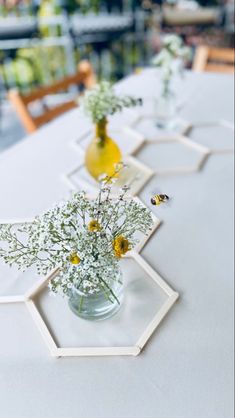 three vases filled with flowers sitting on top of a white tablecloth covered table