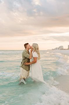 a man and woman kissing in the ocean