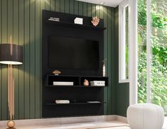 a living room with green walls and a black entertainment center next to a white chair