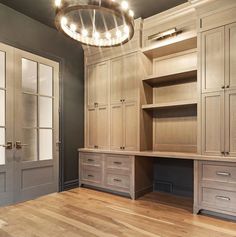 an empty room with wooden flooring and built - in cabinets on the wall, along with a chandelier hanging from the ceiling