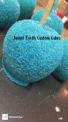 blue cake pops with toothpicks in them on a table next to the words sweet teeth custom cakes