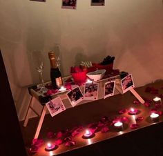 a table with candles and pictures on it, surrounded by rose petals in the shape of hearts