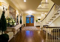 a foyer with stairs and flowers on the table