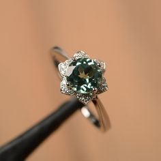 It is a lab green sapphire ring. The main stone is 7 mm*7 mm round cut).weight about 1.66 carats. The basic metal is sterling silver and plated with rhodium/14k white gold/14k rose gold/14k yellow gold You can also go to my shop Home for more elegant rings: https://www.etsy.com/shop/godjewelry?ref=hdr_shop_menu Customization is always welcome and please feel free to contact with me if you have any design ideas! Elegant Green Sapphire Promise Ring, Green Sapphire Ring With Halo Setting For Promise, Green Cubic Zirconia Round Band Jewelry, Elegant Silver Diamond Ring For May Birthstone, Silver Sapphire Ring With Accent Stones For May Birthstone, Green Sapphire Jewelry With Halo Setting, Green Emerald Ring In 14k White Gold Round Cut, Green Sapphire Solitaire Diamond Ring, Silver Sapphire Ring With Prong Setting For May Birthstone