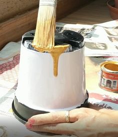 a person holding a paintbrush in front of a white and black brush holder on a table