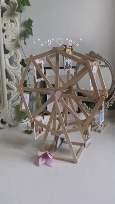 a ferris wheel made out of wooden sticks and pictures on the wall next to a mirror