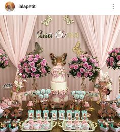 a table topped with lots of cakes and cupcakes covered in frosting next to pink flowers