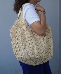 a woman carrying a crocheted bag on her shoulder