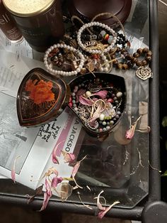 an assortment of jewelry is sitting on top of a table next to a coffee cup