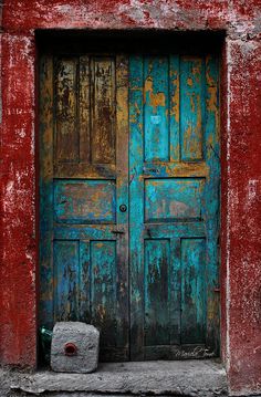 an old red and blue building with two wooden doors