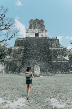 a woman walking in front of an ancient structure